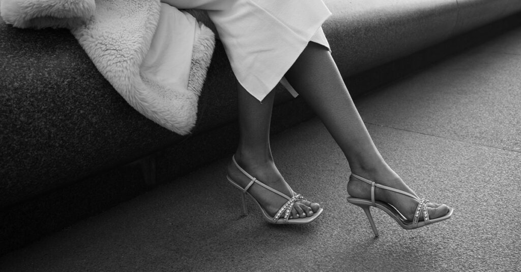 A black and white image of a woman wearing heels, ready to explore the trampling fetish with a client.