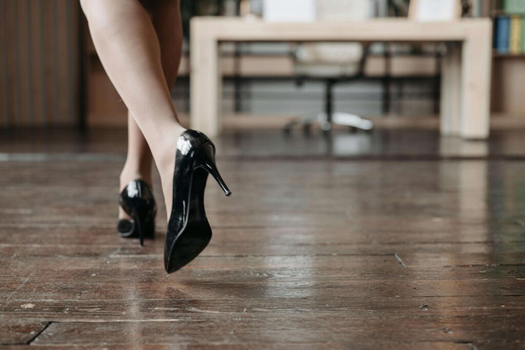 A woman walking with purpose in black high heels across a wooden floor to symbolise BDSM in foot fetish, particularly the domination aspect.