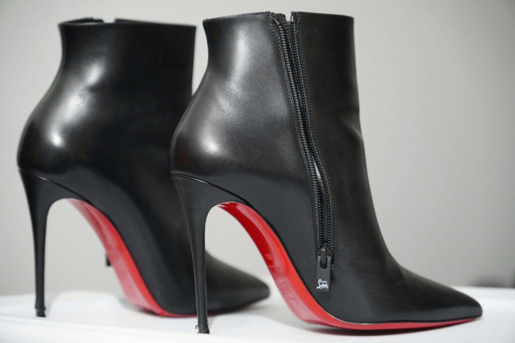 A pair of black heeled boots with red soles to symbolise boot fetishism.